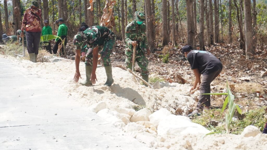 Perkokoh Bahu Jalan dan Keamanan Akses Desa, Satgas TMMD 129 dan Warga Uruk Sisi Jalan Rabat Beton Gunakan Padel